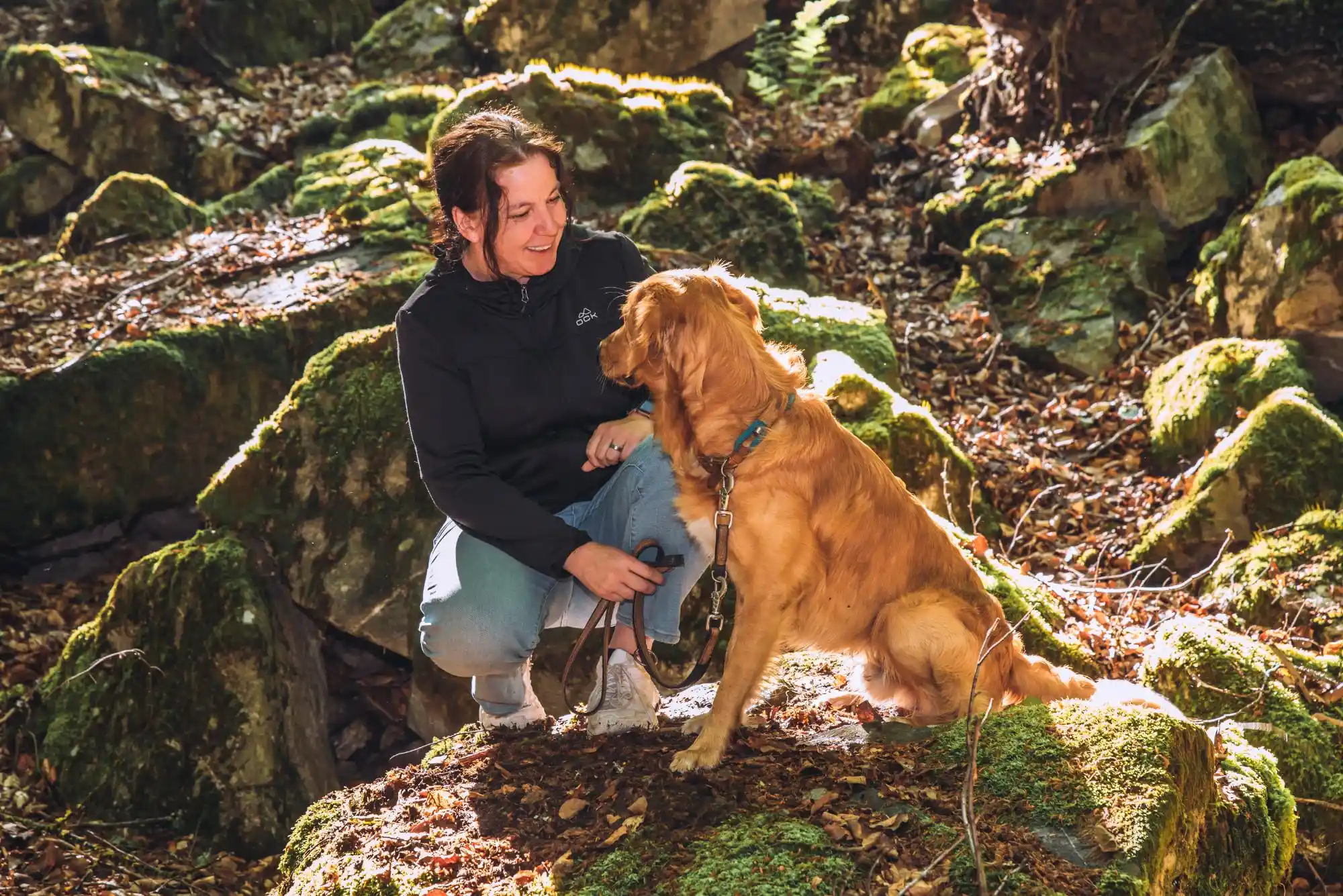 Kerstin Ehses wendet sich einem sitzenden Golden Retriever zu; beide schauen einander an.